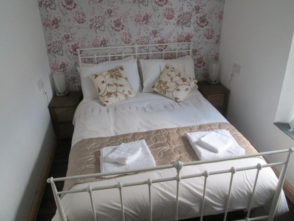 een bed met witte lakens en kussens in een slaapkamer bij The Hub at Abercrave in Abercraf