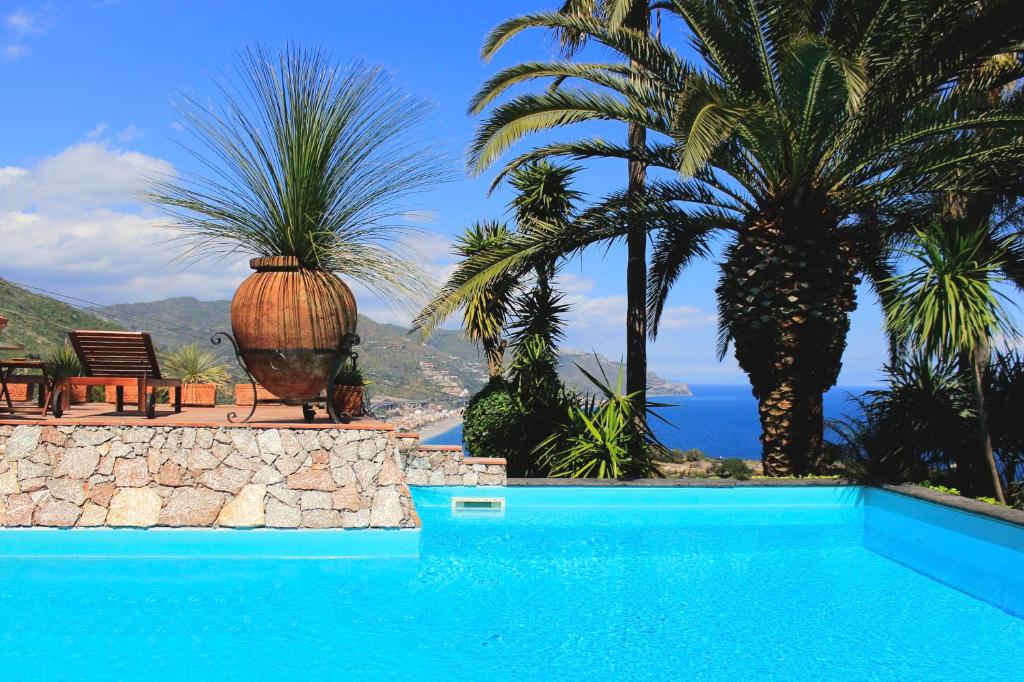 una piscina con palme e vista sull'oceano di VILLA LOU TAORMINA Private Villa with Panoramic Sea View Pool a Taormina