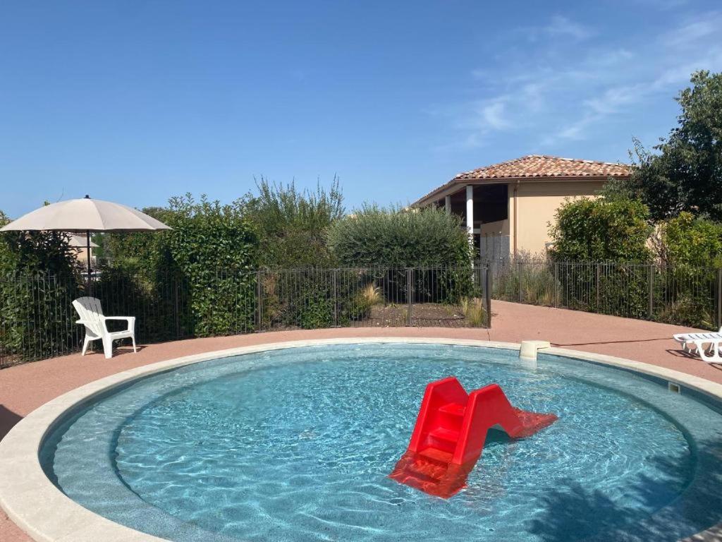 - une piscine avec 2 chaises rouges dans l'eau dans l'établissement Bastidon PMR aux Demeures du Ventoux, à Aubignan
