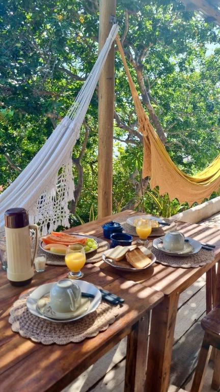 a wooden table with plates of food and glasses of orange juice at Chalé Green Vila Mathilde in Icapuí