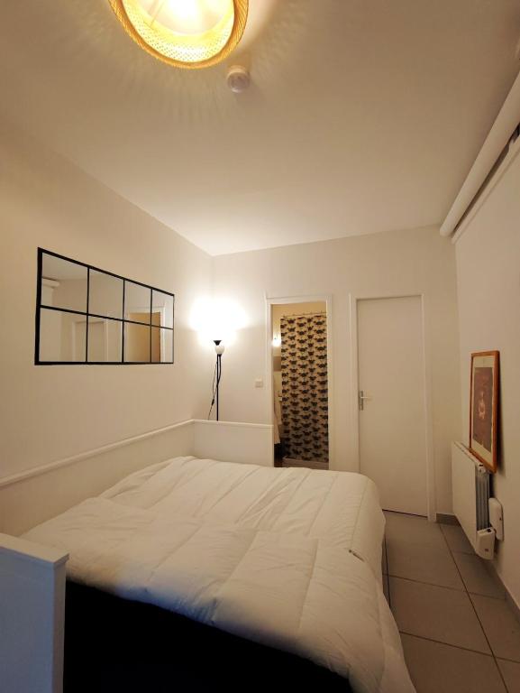 - une chambre avec un grand lit blanc et une lumière dans l'établissement Cosy studio 14m2 centre-ville, à Villeurbanne