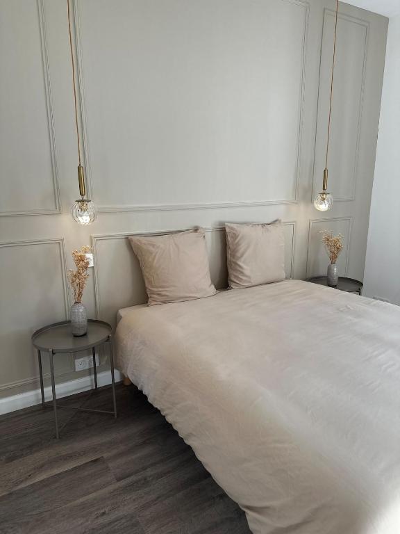 - un lit blanc avec deux oreillers et une table dans l'établissement Les Jasmins - Centre Ville de Saumur, à Saumur