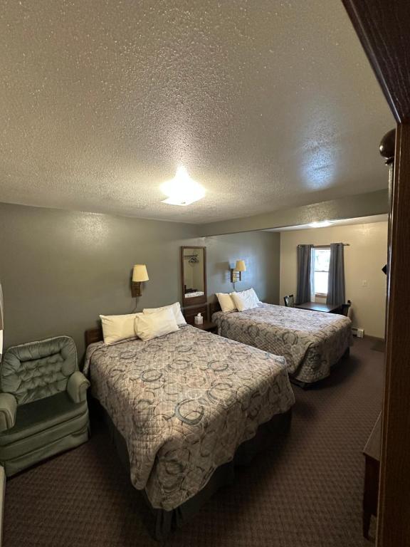 a hotel room with two beds and a chair at Sportsman Motel in Malta