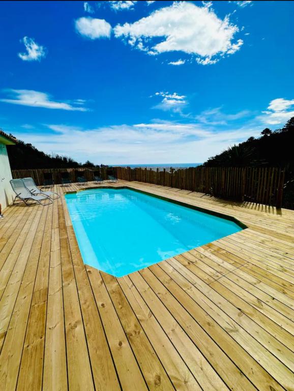 - une piscine bleue sur une terrasse en bois dans l'établissement Villa Mare è Machja avec piscine et vue mer, à Sari-Solenzara