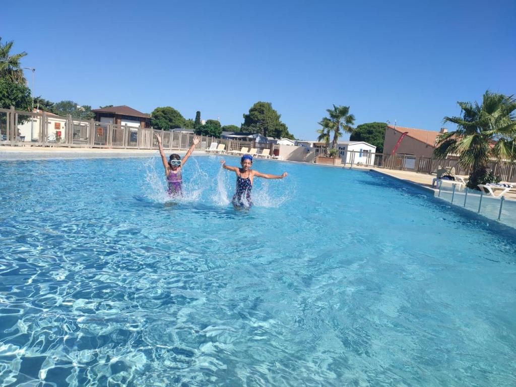 2 personnes se tiennent debout dans une piscine dans l'établissement AU 120 Grand mobilhome clim, à Port-la-Nouvelle