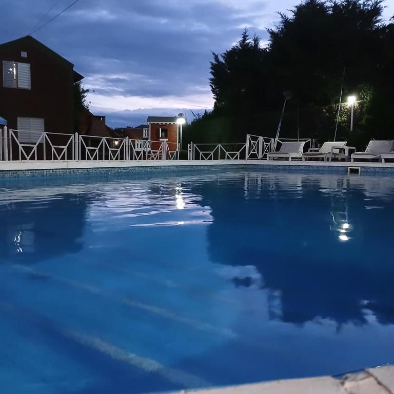 a large swimming pool with blue water at night at Cantonavi Cabañas in Mina Clavero