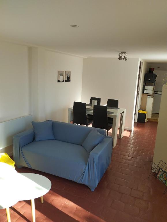 un salon avec un canapé bleu et une table dans l'établissement Appartement à la campagne, à Génillé