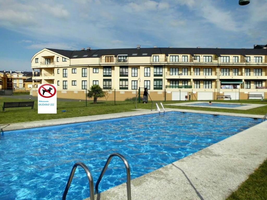 a large building with a swimming pool in front of it at Zona Las Catedrales Barreiros Playa de Altar in Villadaíde