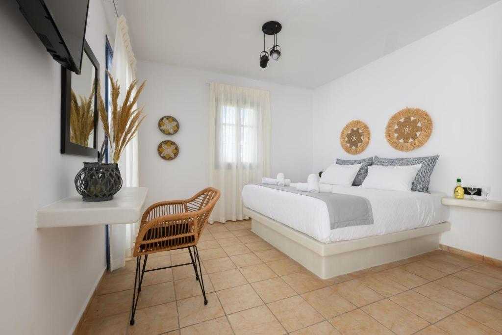 a white bedroom with a bed and a chair at Blue Heart Luxury Suites in Agia Anna Naxos