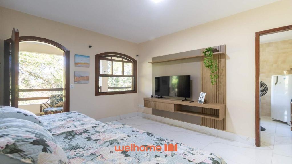 Un dormitorio con una cama y un televisor en una pared. en Apartamento em Miguel Pereira com Varanda Ampla, en Miguel Pereira