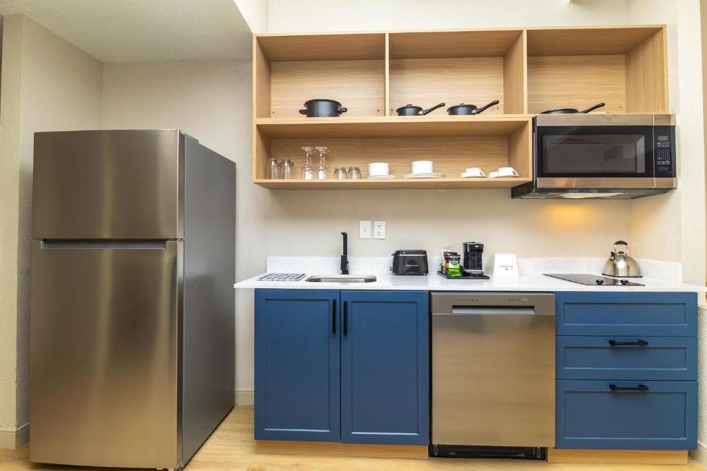 a kitchen with blue cabinets and a stainless steel refrigerator at Ramada by Wyndham Davenport Orlando South in Davenport