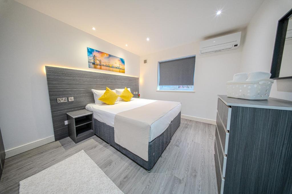 Un dormitorio con una cama grande con almohadas amarillas. en Ilford Luxury Apartments, en Ilford