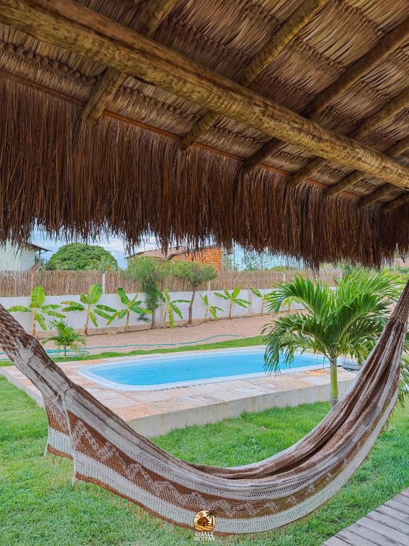 a hammock under a straw umbrella in a resort at Moitas Chalés in Amontada