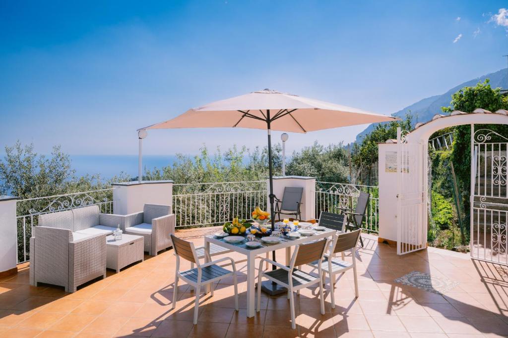 a patio with an umbrella and a table and chairs at Infinity Experience Casa Vacanza Incantevole con Terrazzo in Scala