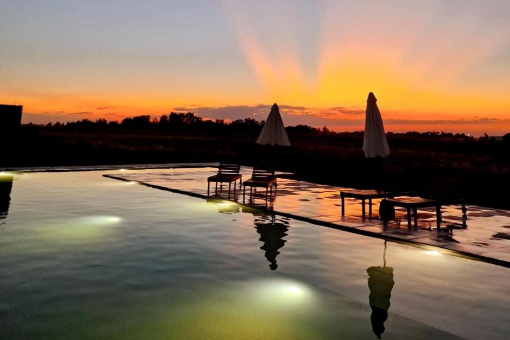a pool of water with tables and umbrellas at sunset at Casa de Campo Calcaterra in Miramar