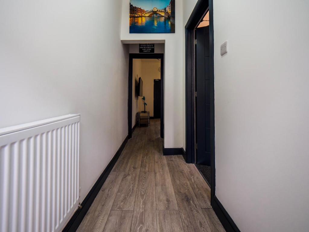 un pasillo con paredes blancas, suelo de madera y una pintura en Chatham lodge Cosy Large Double Room 1, en Stoke on Trent