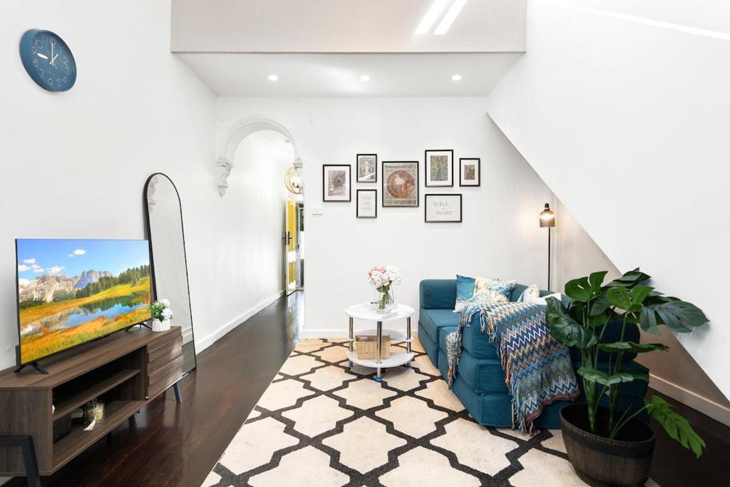 Una sala de estar con un sofá azul y un televisor en Cozy House near Darling Harbor, en Sídney