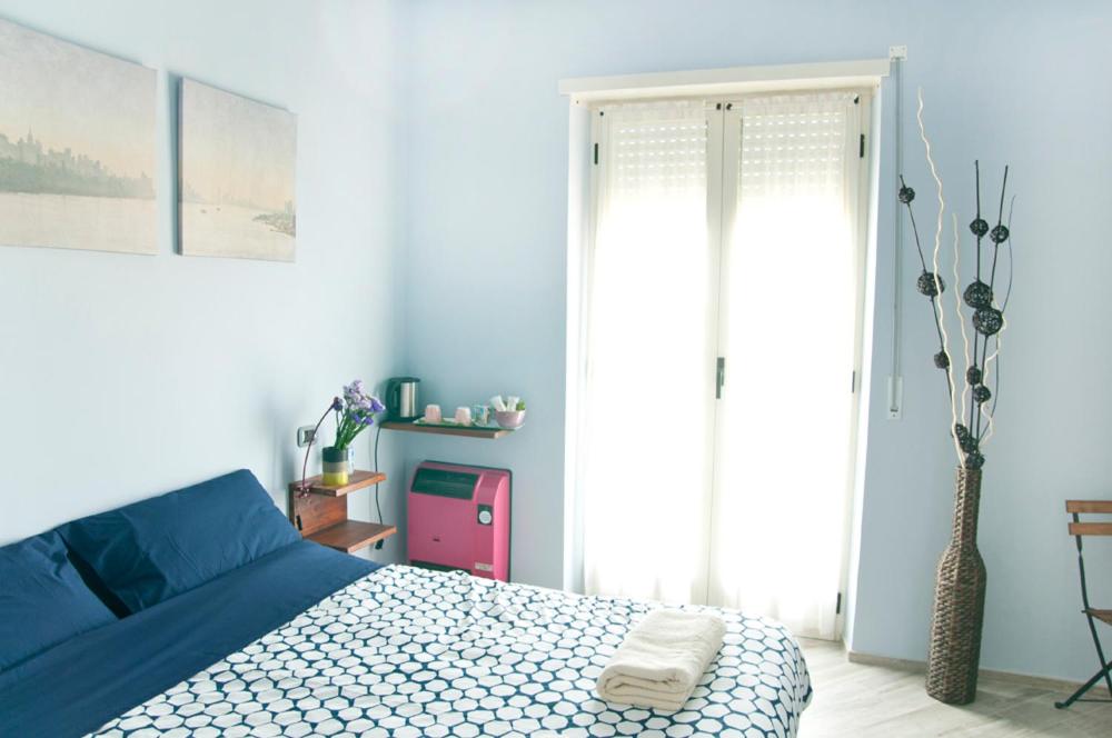 a bedroom with a blue bed and a window at Blueberry Rooms in La Morra