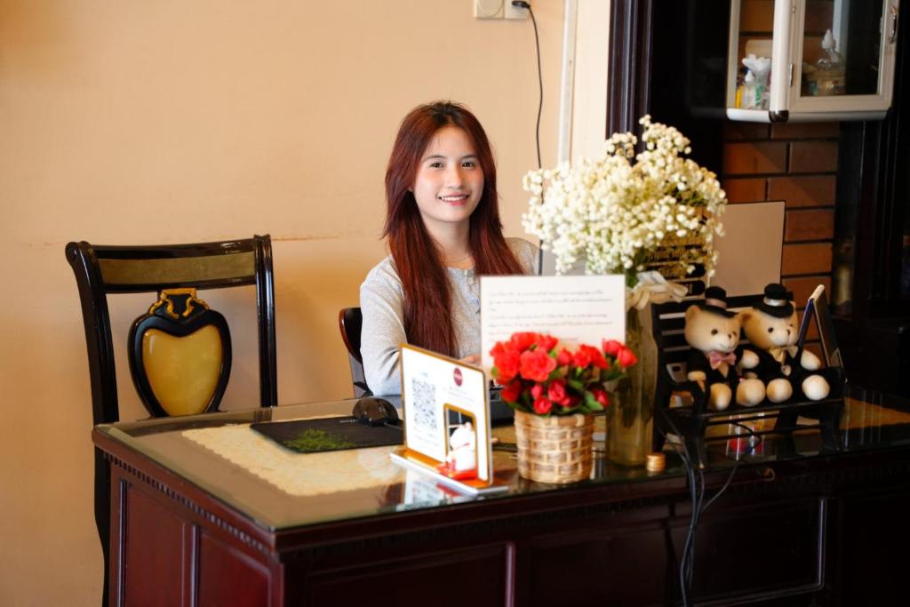 フエにあるPerfume Homestay Huếの看板を持つ机に座る女性