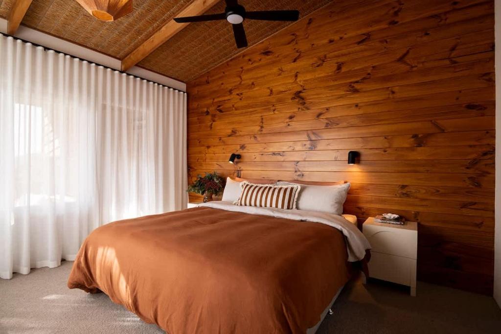a bedroom with a bed and a wooden wall at Coastal Tree House- Short Stroll to Beach in Encounter Bay