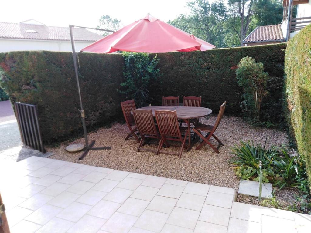 - une table et des chaises avec un parasol dans le jardin dans l'établissement Appartement 5 personnes près plage Nauzan avec terrasse, animaux acceptés - FR-1-494-210, à Vaux-sur-Mer