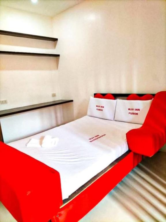 a red bed with white sheets and red pillows at WJV Inn Cordova II in Cordova