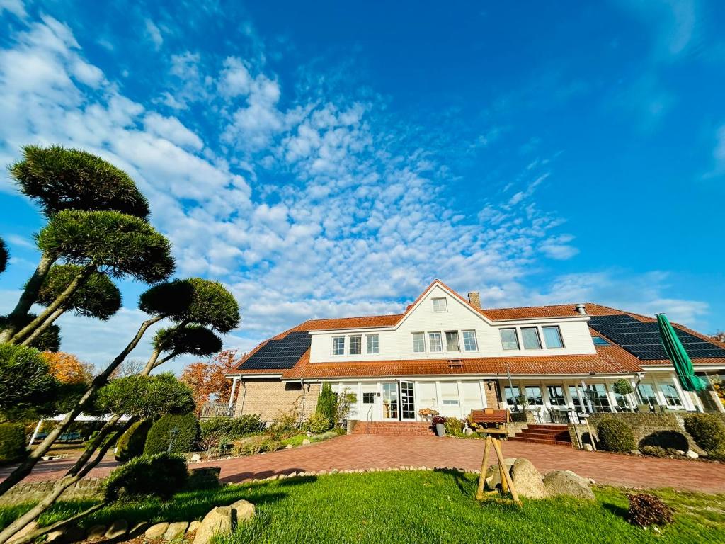 a white house with a landscaped yard at Hotel Reindahls in Wilkendorf