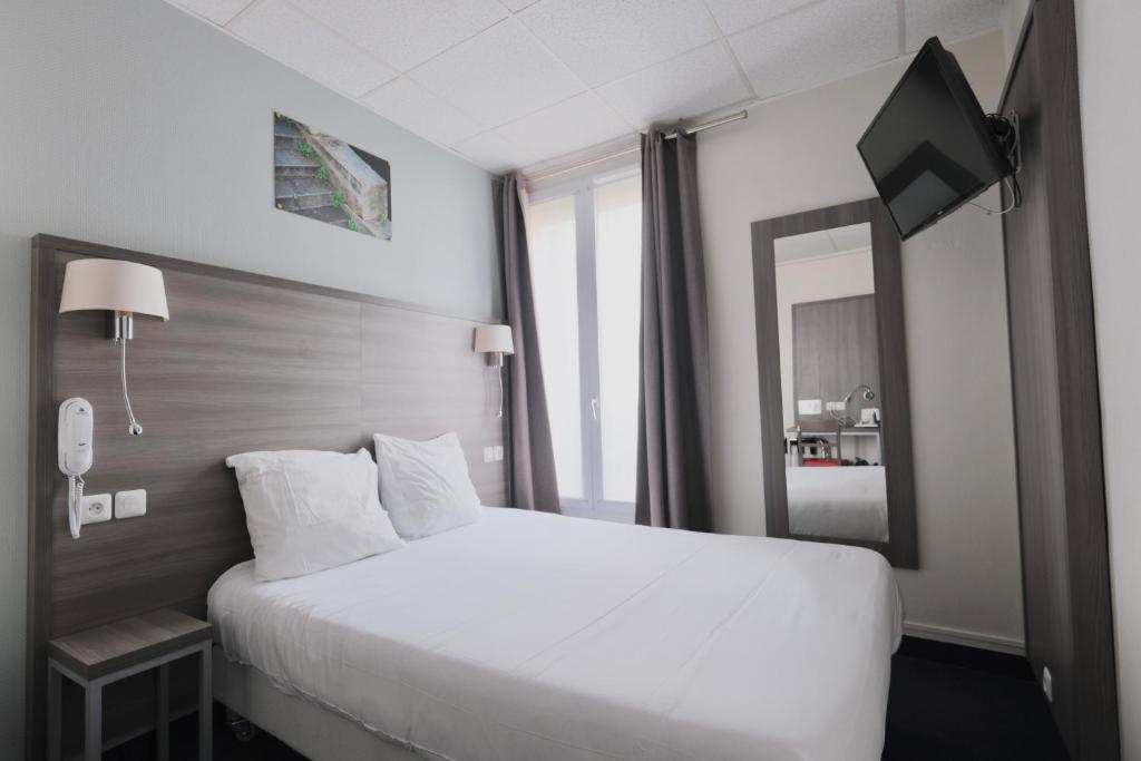 a hotel room with a white bed and a mirror at Hotel Lilas Gambetta in Paris