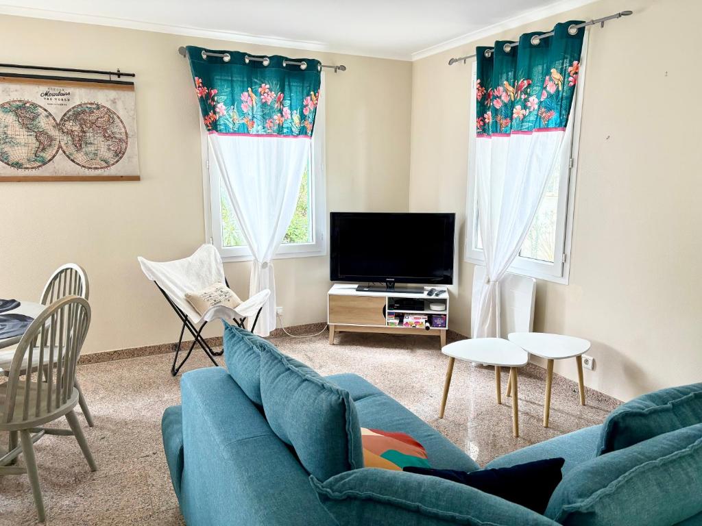 un salon avec un canapé bleu et une télévision dans l'établissement La maison des Epinouses, 4 chambres à 450M de la plage de Chaucre, à Saint-Georges-dʼOléron