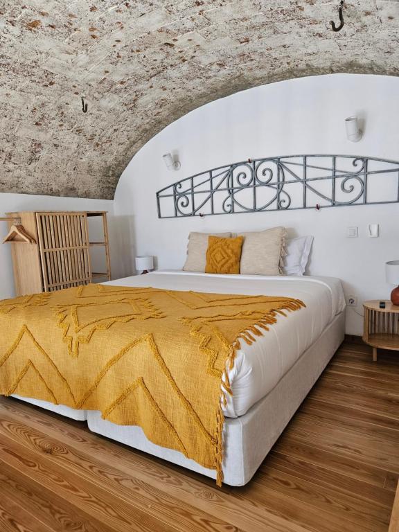 a bedroom with a white bed with a yellow blanket at Solar de Arrayollos by PURUS in Arraiolos