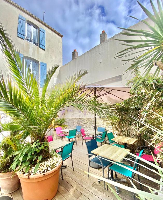 un patio avec tables, chaises et palmiers dans l'établissement Maison Richet, à Les Sables-dʼOlonne