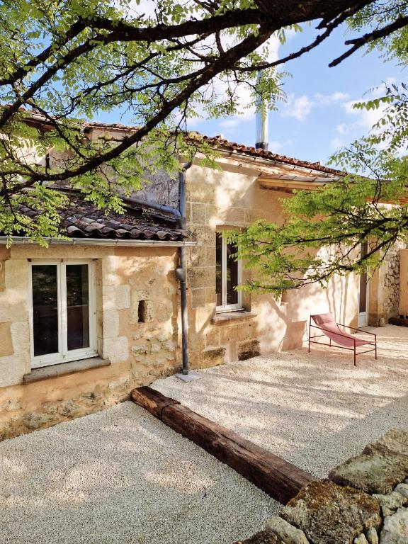 une maison avec un banc rouge devant elle dans l'établissement Gîte Vin'acacia, à Saint-Romain-la-Virvée
