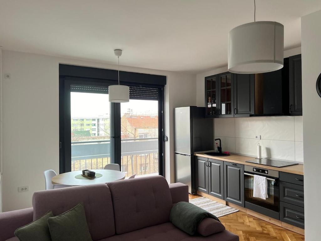 a living room with a couch and a table in a kitchen at Lux stan na dan in Novi Sad