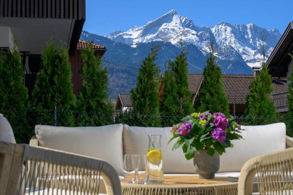 een tafel met een vaas met bloemen op een balkon met bergen bij BergHome in Garmisch-Partenkirchen