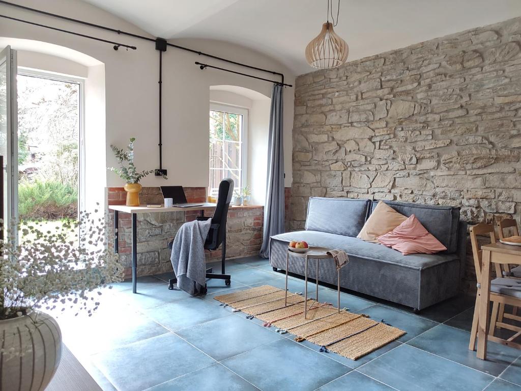 a living room with a couch and a stone wall at Apartamenty KDN Garden in Bielsko-Biała