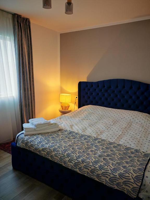 a bedroom with a bed with a blue headboard and a window at Cabanuta in Brașov in Braşov