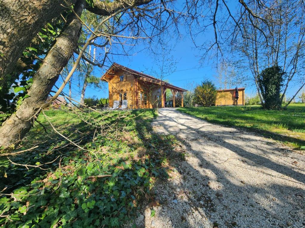 a dirt road leading to a wooden house at Le Chalet « au Fil de l’eau » in Véreux