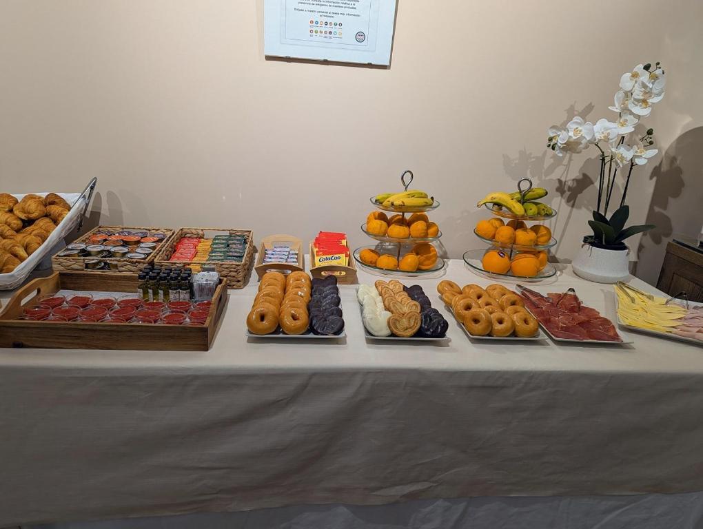 a table with different types of donuts and other foods at Hotel de Francia y París in Cádiz