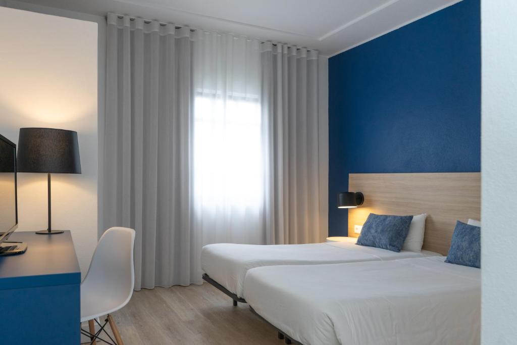 a hotel room with two beds and a desk and a window at Flag Hotel Santarém in Pernes
