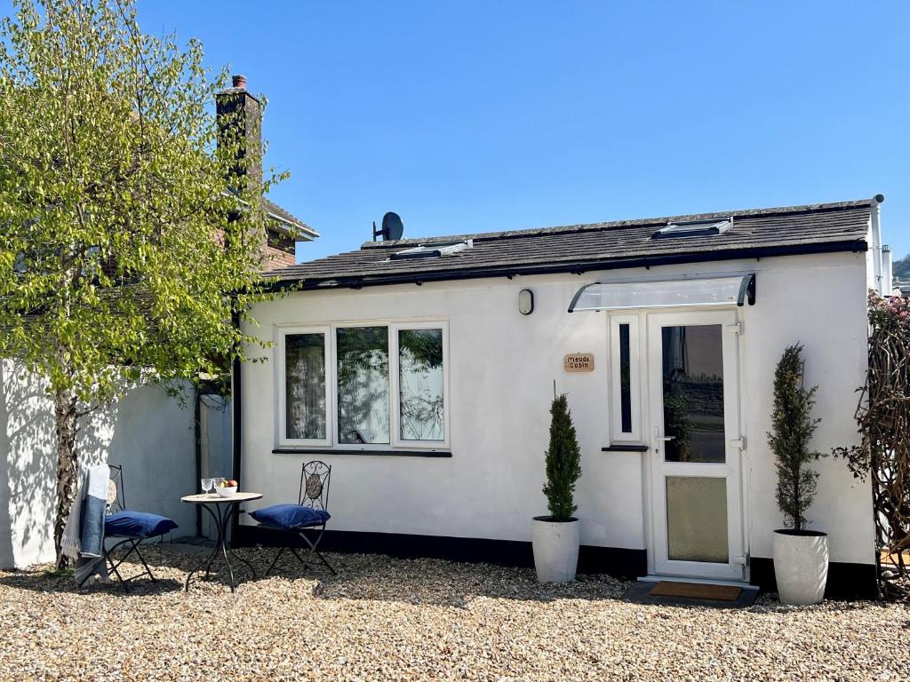 a white house with two chairs and a table at Meads Cabin in Charmouth