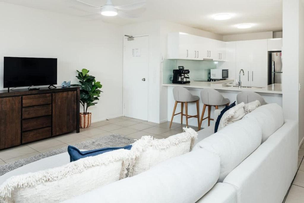 a living room with a white couch and a television at Marcoola Sands 6 - Pool to Beach in Marcoola