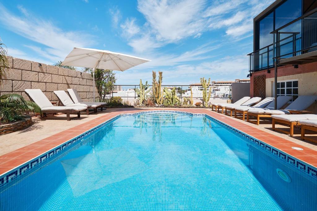einem Pool mit Stühlen und einem Sonnenschirm auf einem Gebäude in der Unterkunft Casa del Mirador Ocean VIEW private heated pool in Playa Paraiso