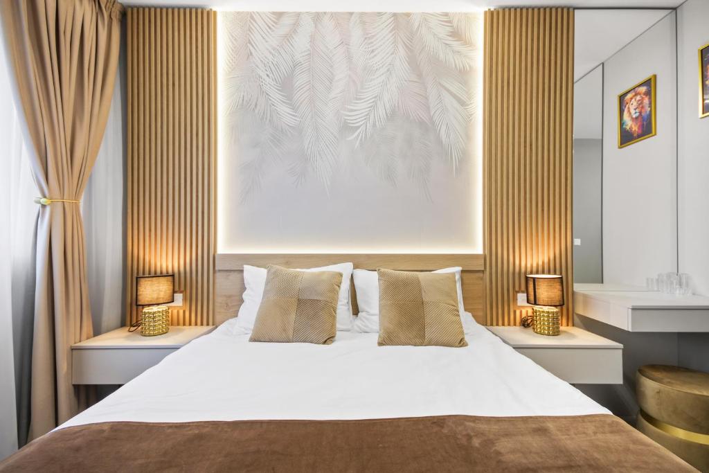 a bedroom with a large bed with two lamps at Hils Pallady Apartments in Bucharest