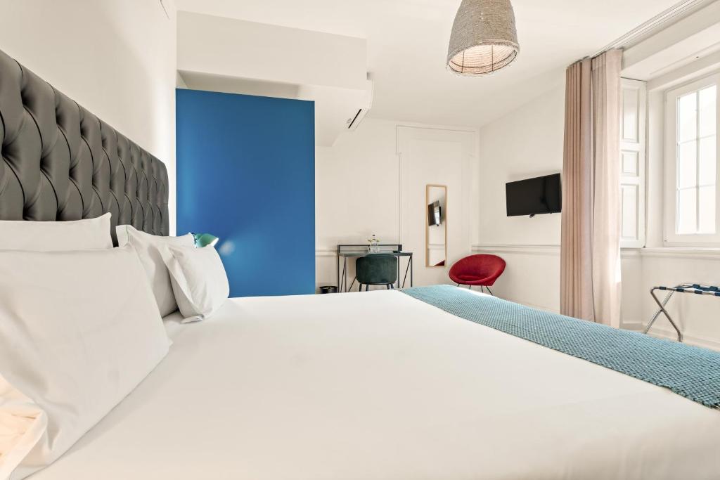 A bright bedroom with a blue accent wall, large window and red chair.