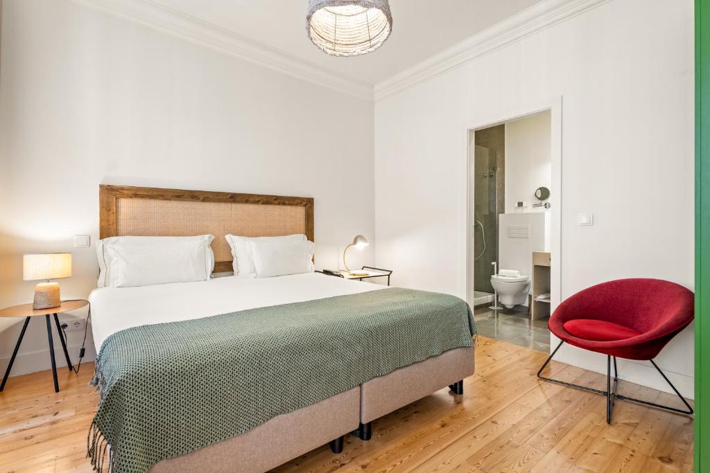 A double bedroom with a wood-framed bed, red accent chair and ensuite entrance.