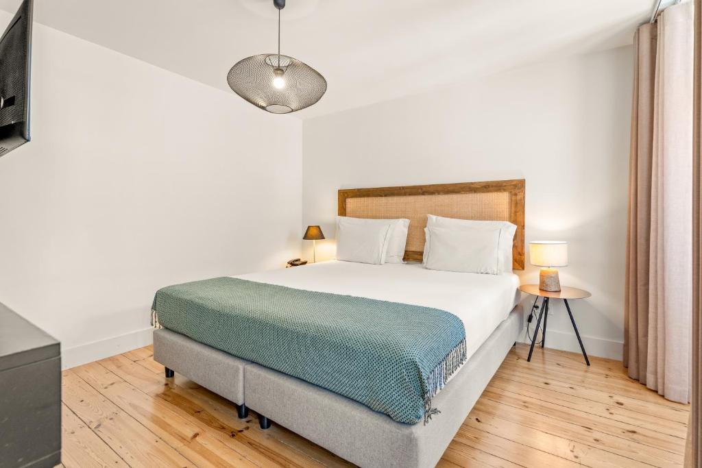 A simple double bedroom with a wood headboard, bedside tables and curtained window.