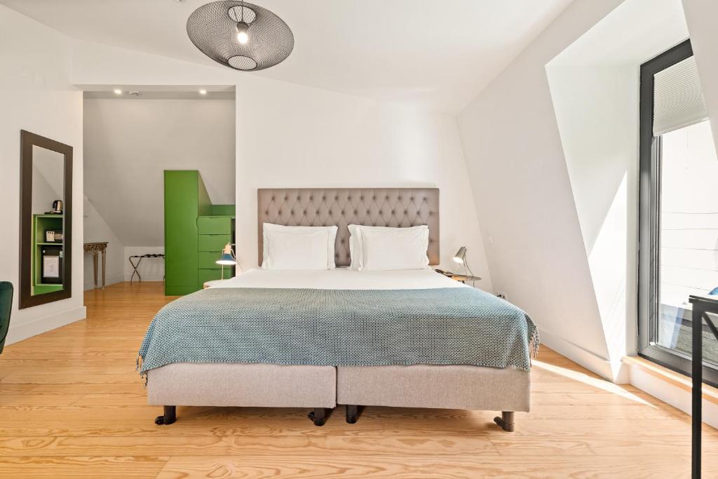 A bright double bedroom with a sloped ceiling, large glazed opening and green built-in storage.
