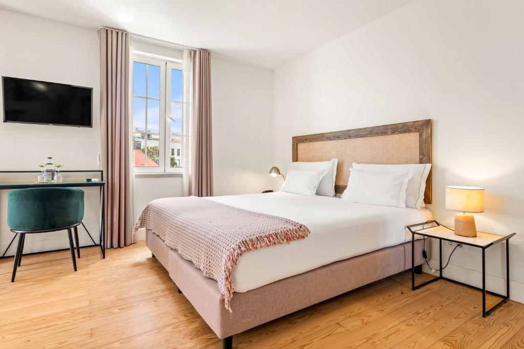 A bright bedroom with a large bed, window, television and compact desk.