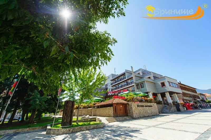 a street with a tree and buildings in the background at Хотел Добринище in Dobrinishte