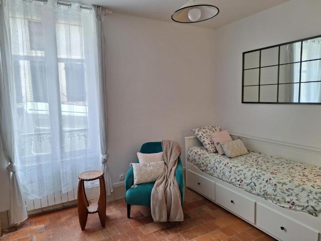 a bedroom with a bed and a chair and a window at Les Remparts 1 in La Charité-sur-Loire